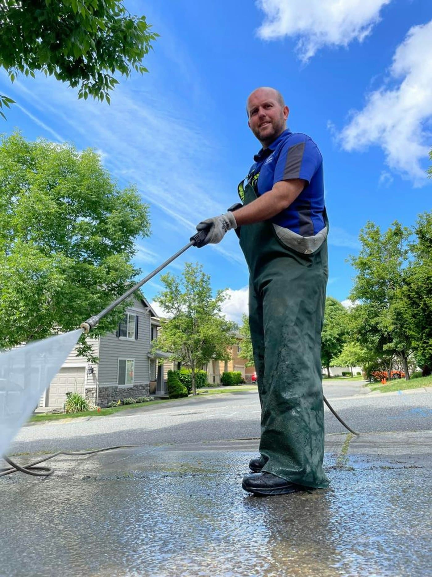 Pressure washing a driveway in front of a house